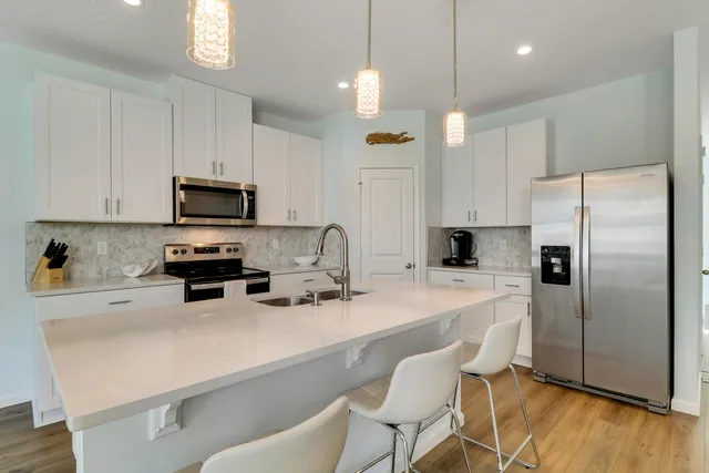 a kitchen with refrigerator a stove a sink and chairs
