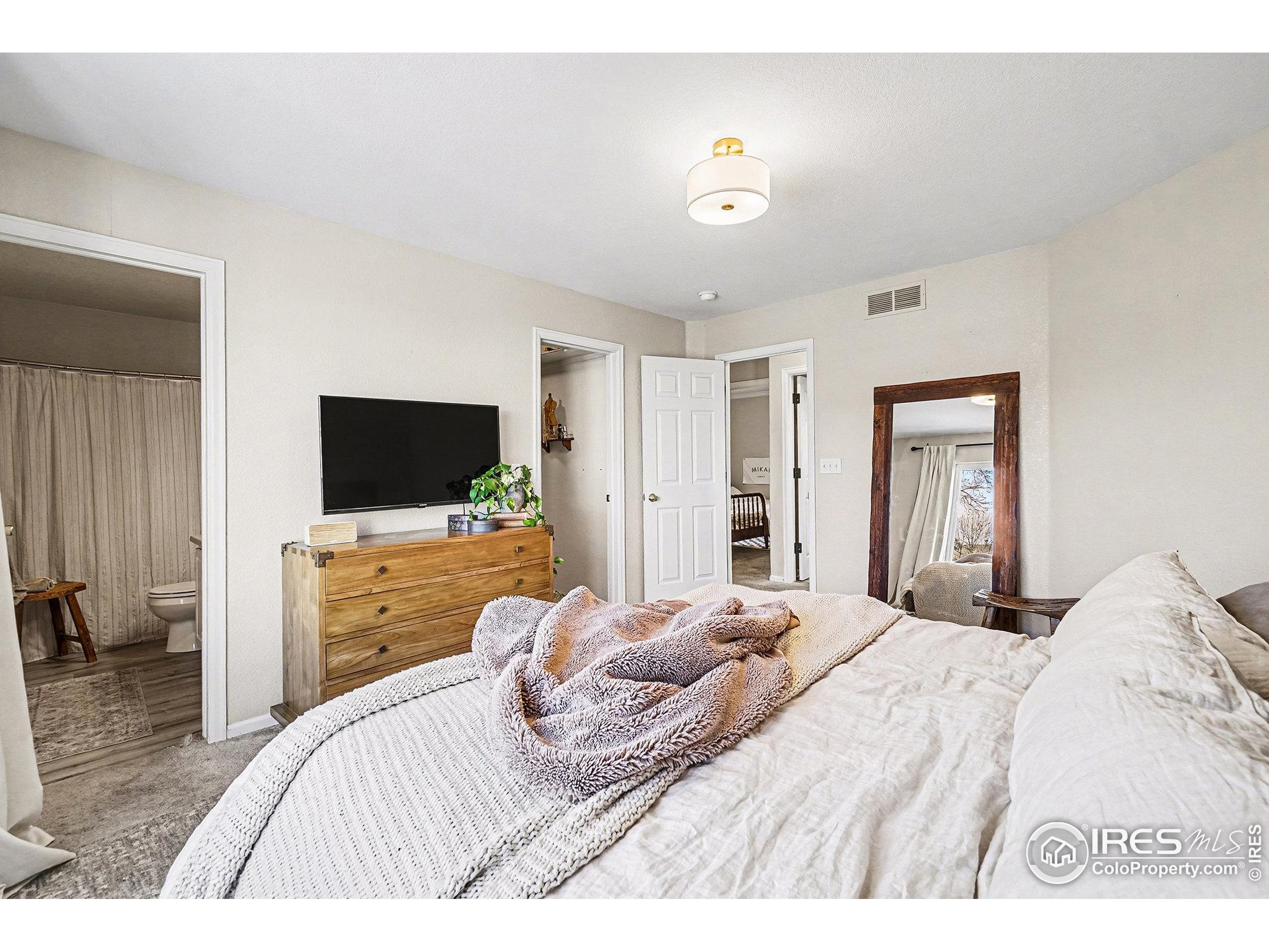 1244 Spring Creek Court Longmont, CO 80504 - Photo 14 of 32 a bedroom with a bed and a flat screen tv