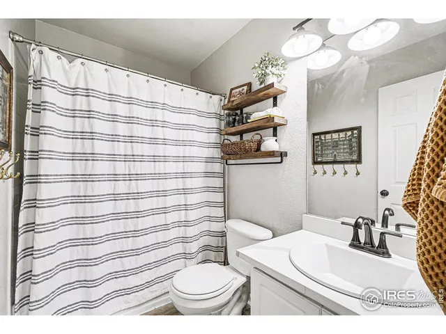 a bathroom with a sink a toilet a mirror and shower curtain