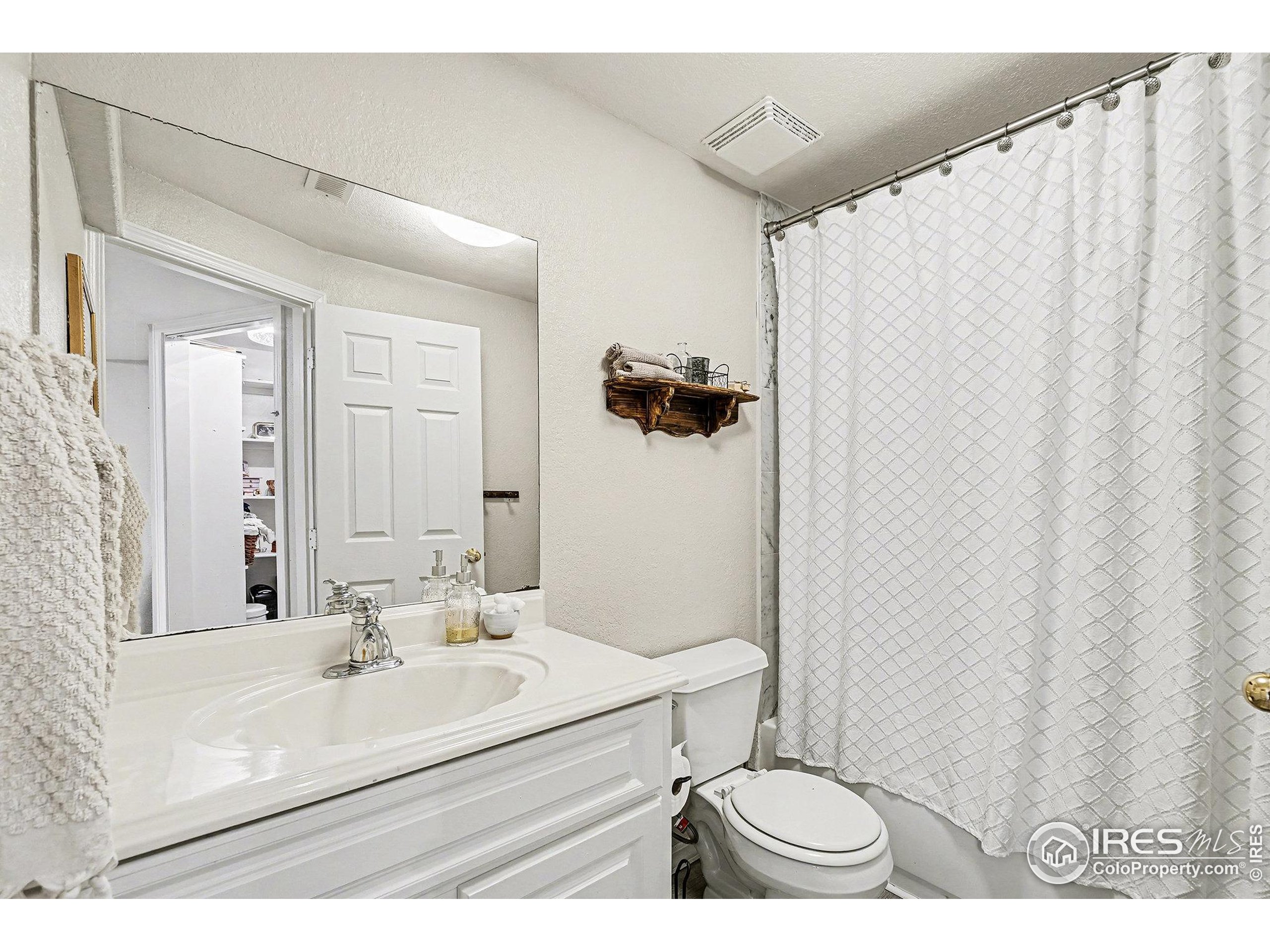 1244 Spring Creek Court Longmont, CO 80504 - Photo 26 of 32 a bathroom with a sink toilet a mirror and shower
