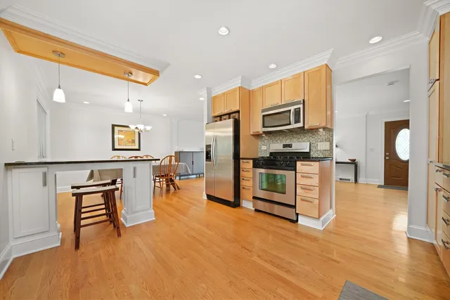 a kitchen with stainless steel appliances kitchen island granite countertop a refrigerator a stove a oven and white cabinets with wooden floor