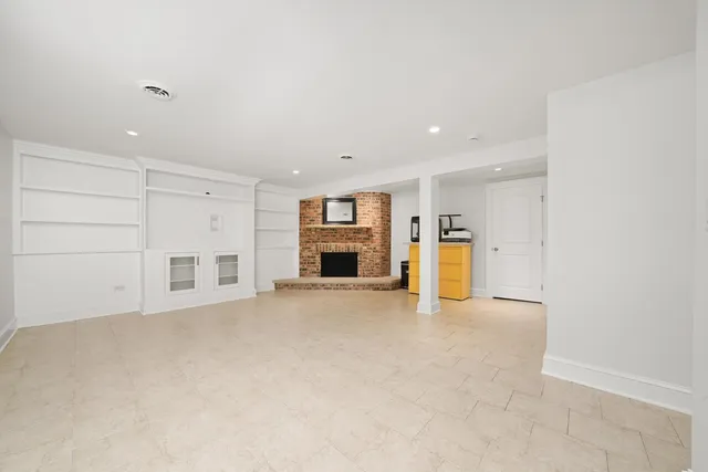 an empty room with a kitchen and a fireplace