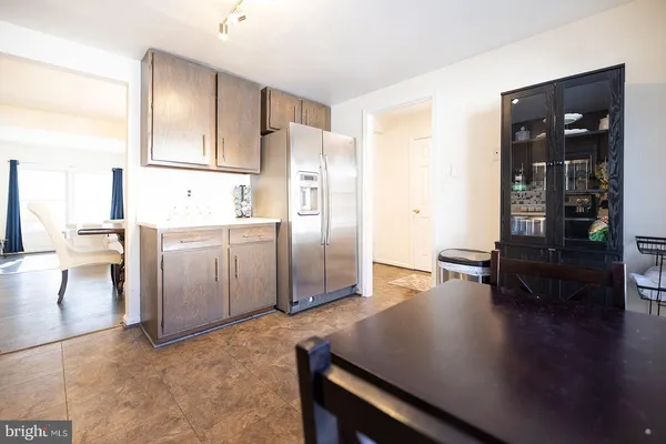 a kitchen with stainless steel appliances a refrigerator a stove and a dining table with wooden floor