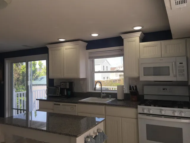 a kitchen with granite countertop a stove a sink and a microwave