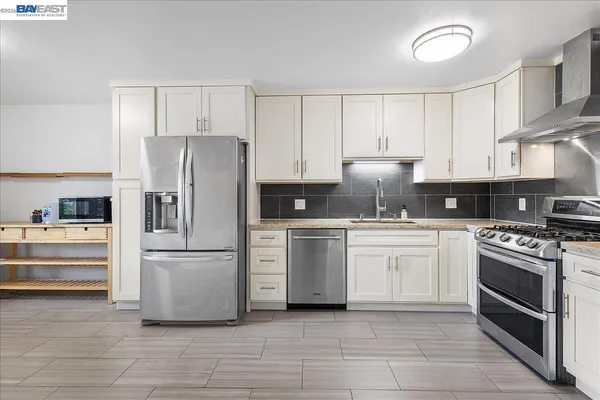a kitchen with stainless steel appliances granite countertop a stove a sink and a refrigerator