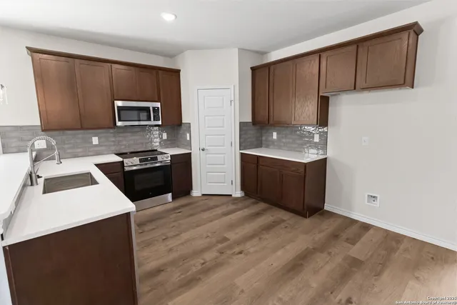 a kitchen with stainless steel appliances a sink a stove a microwave a sink a refrigerator and cabinets