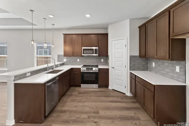 a large kitchen with a large counter top a stove a sink and refrigerator