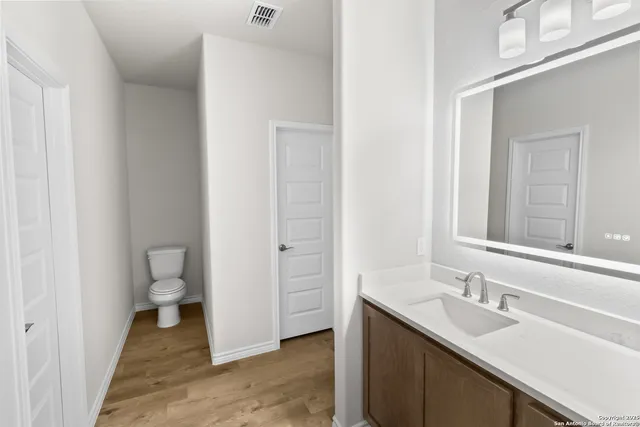 a bathroom with a granite countertop sink toilet and a mirror