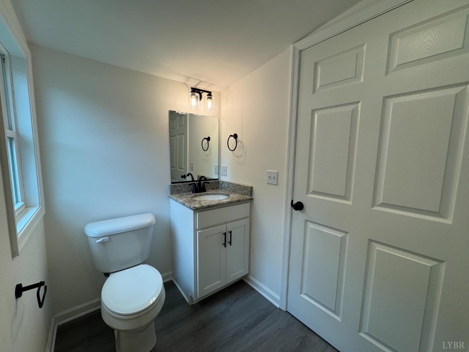 287 Harrell Street Appomattox, VA 24522 - Photo 14 of 17 a bathroom with a granite countertop toilet a sink and a mirror
