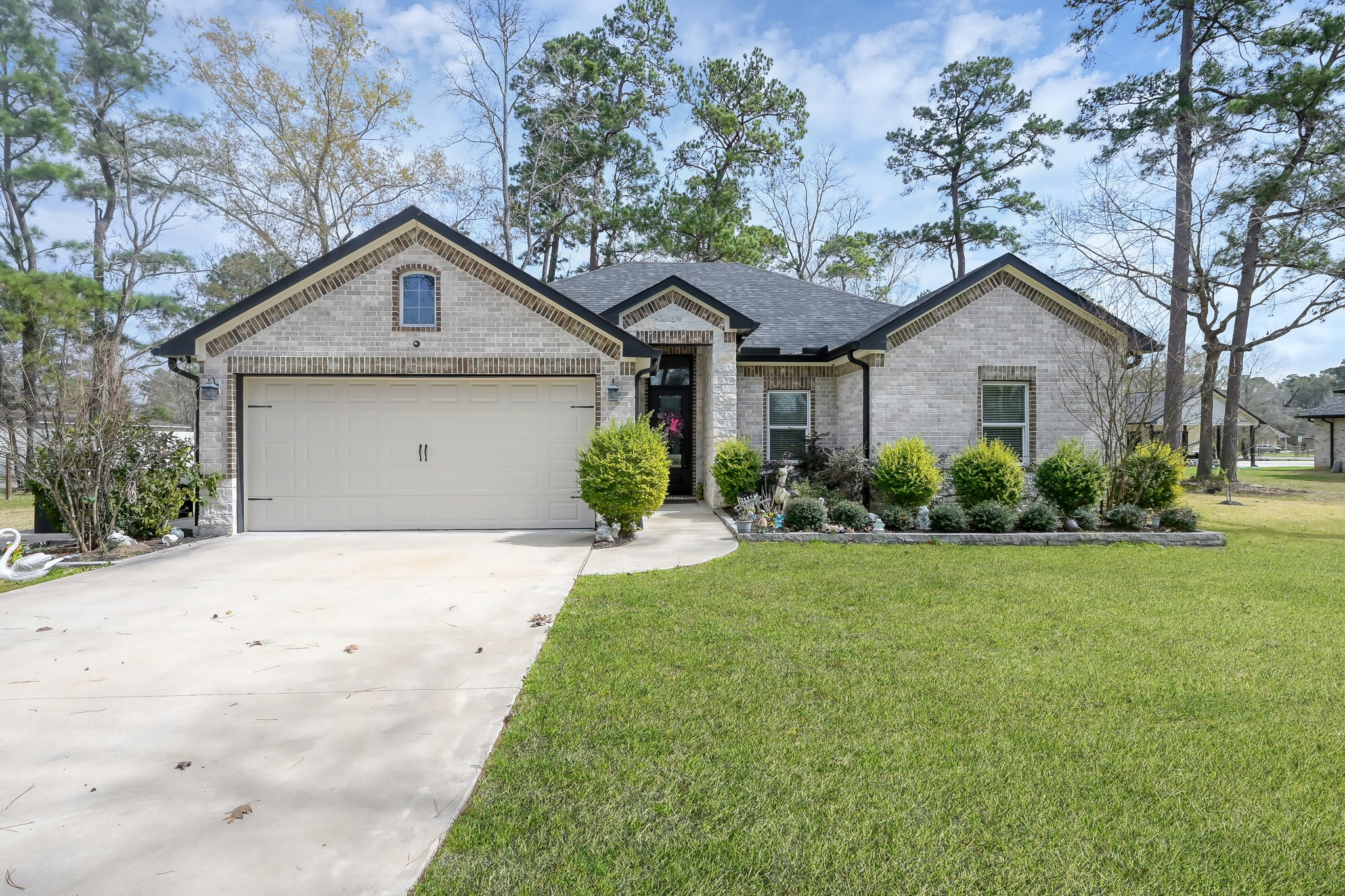a front view of a house with a garden and trees