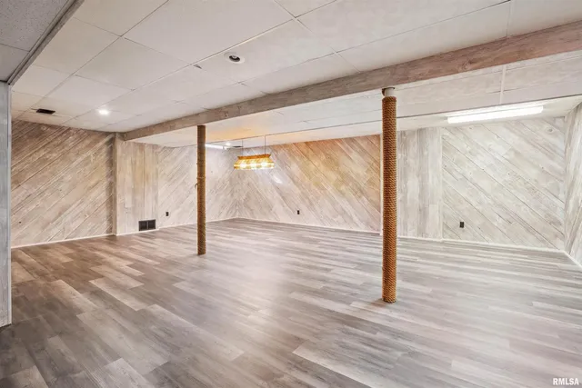 a view of an empty room with wooden floor and windows