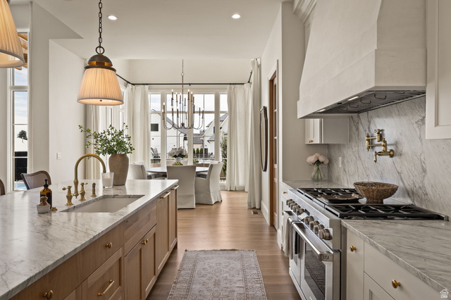 478 South Maple Lakes Drive Mapleton, UT 84664 - Photo 6 of 51 Gourmet kitchen featuring a large central island with an integrated sink, professional-grade range, full-height stone slab backsplash, and wood-finish flooring