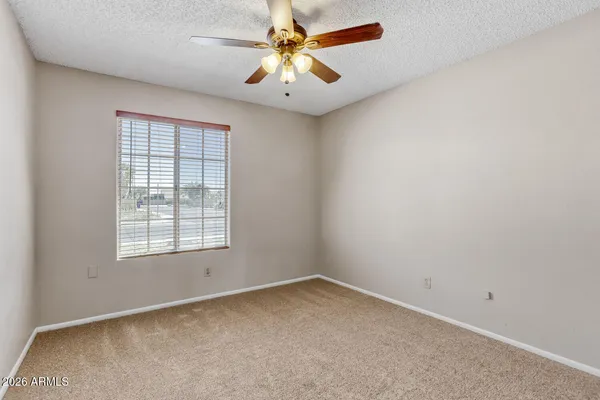 an empty room with a window and a fan