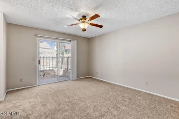 an empty room with chandelier fan and windows