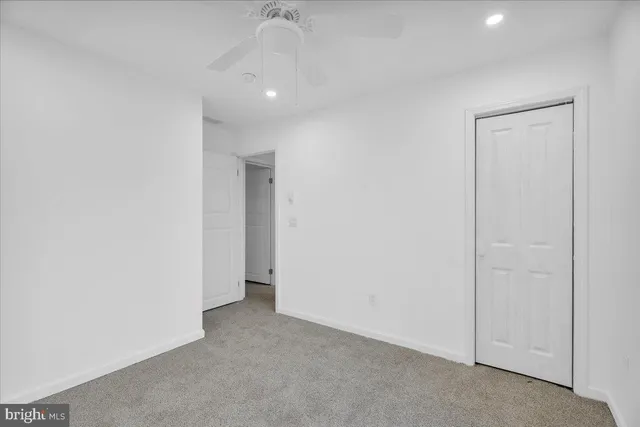 an empty room with a ceiling fan and carpet