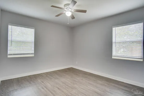 a view of empty room with wooden floor and fan