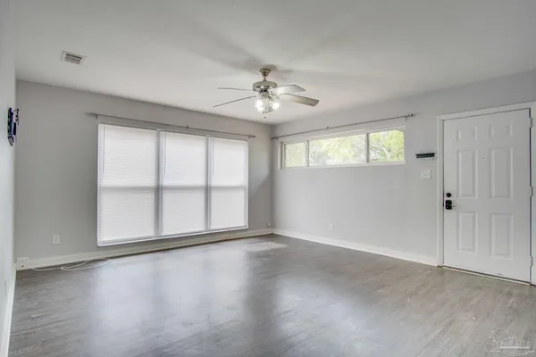 an empty room with wooden floor and windows with curtains