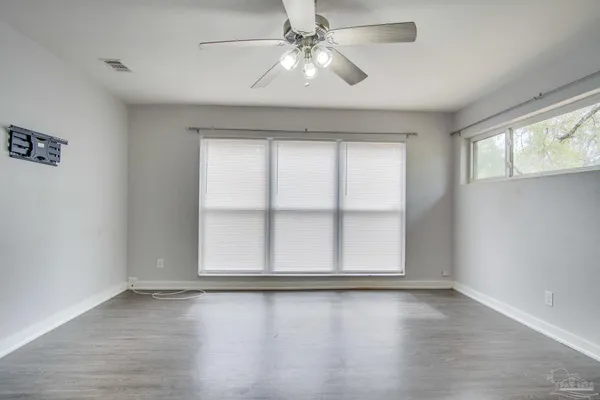 an empty room with wooden floor chandelier and windows