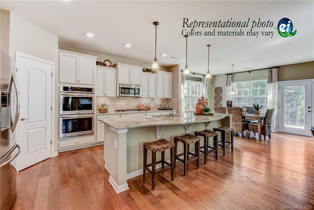 5116 Tranquility Boulevard, Unit 678 Lancaster, SC 29720 - Photo 15 of 21 a open kitchen with stainless steel appliances granite countertop a stove a refrigerator a kitchen island a dining table and chairs with wooden floor