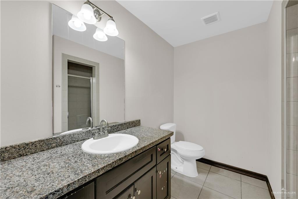 606 North Inspiration Road, Unit 6 Alton, TX 78573 - Photo 11 of 14 a bathroom with a granite countertop sink a toilet and a mirror