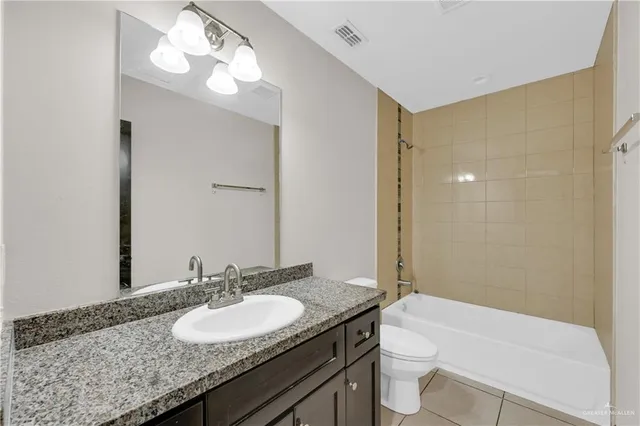 a bathroom with a granite countertop sink a toilet a mirror and shower