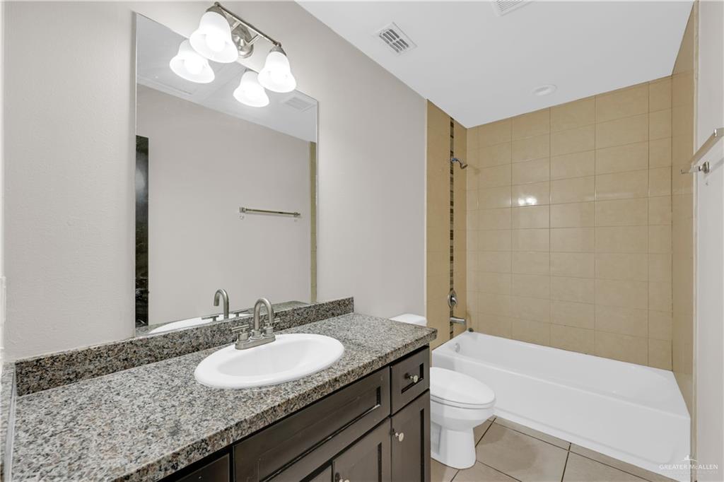606 North Inspiration Road, Unit 6 Alton, TX 78573 - Photo 8 of 14 a bathroom with a granite countertop sink a toilet a mirror and shower