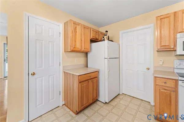 a utility room with granite countertop cabinets and refrigerator