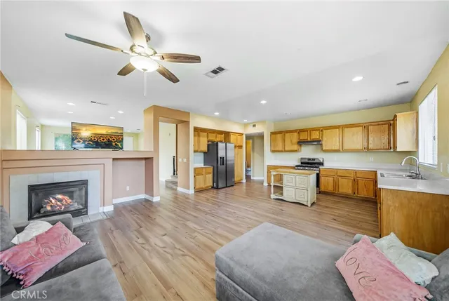 a living room with stainless steel appliances furniture fireplace and flat screen tv