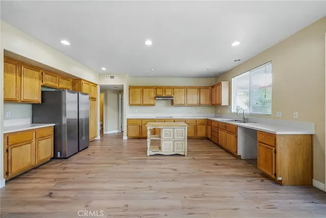 a large kitchen with stainless steel appliances granite countertop a large counter top a sink a stove a refrigerator and cabinets