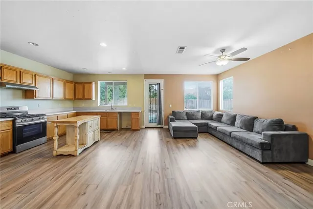 a living room with kitchen island granite countertop wooden floor and stainless steel appliances
