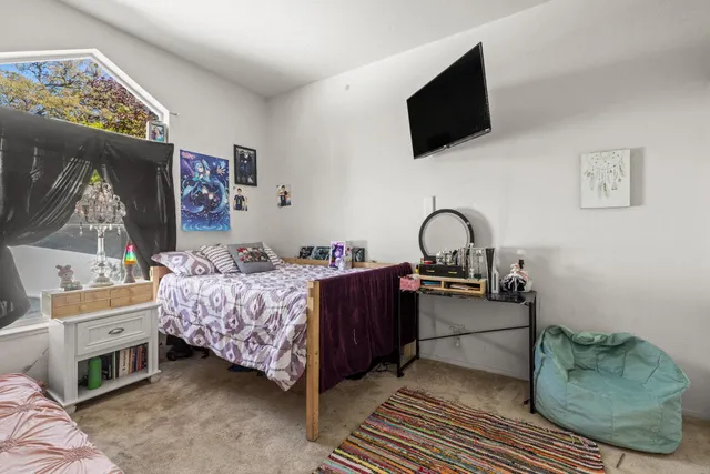 a bedroom with a bed window and flat screen tv