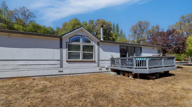 a view of a house with a wooden deck and a yard
