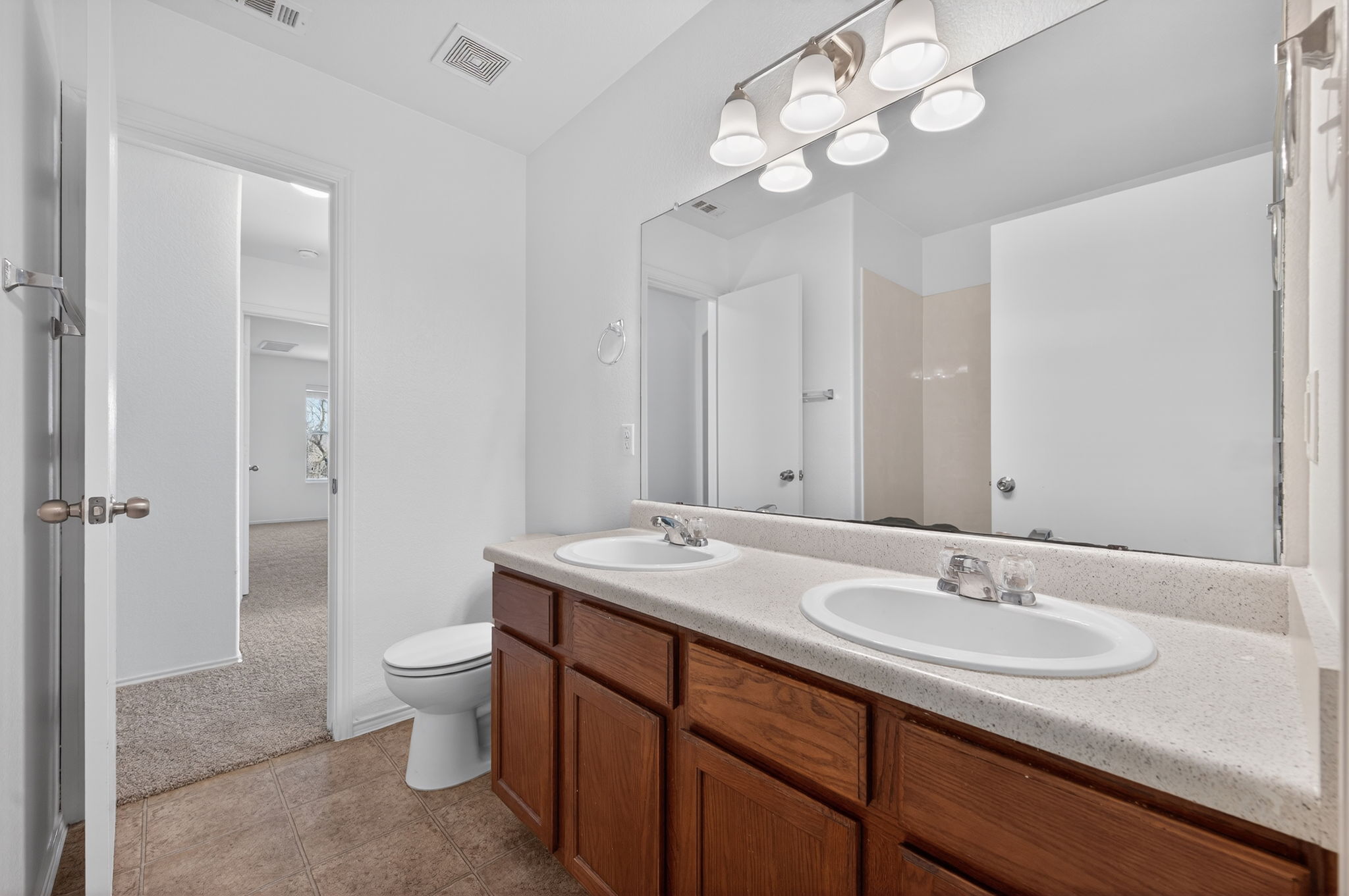 13629 Coomer Path Pflugerville, TX 78660 - Photo 19 of 30 Full bath with double vanity, light carpet, and light tile patterned floors
