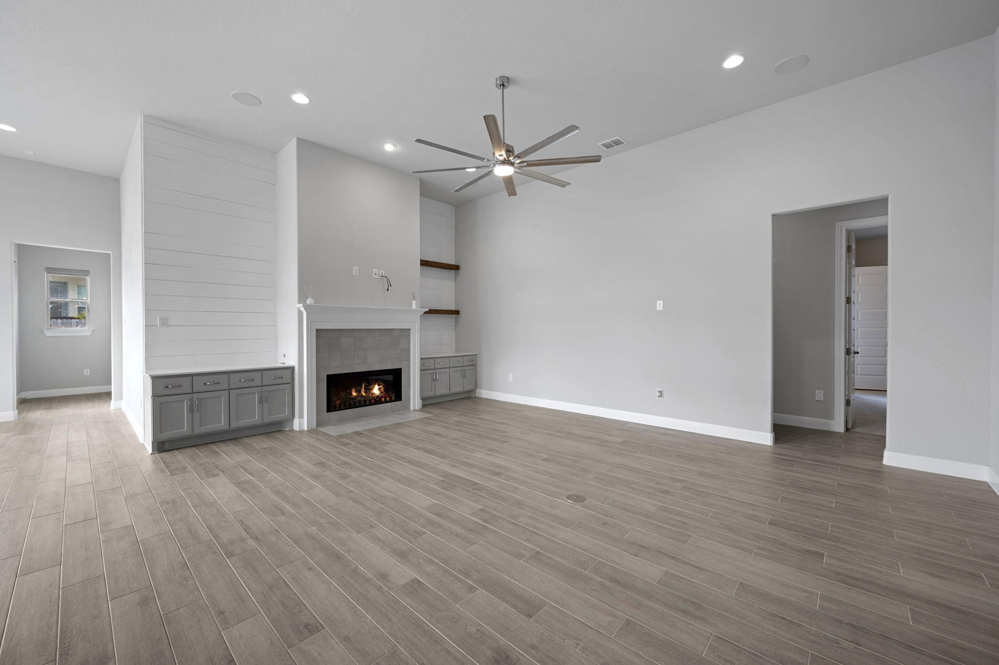 165 Eclipse Drive Austin, TX 78737 - Photo 9 of 38 an empty room with wooden floor a ceiling fan a fireplace and windows