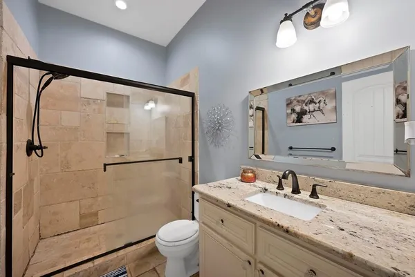 a bathroom with a granite countertop sink toilet and shower