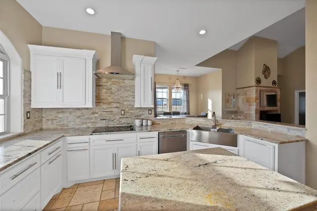 a large white kitchen with stainless steel appliances kitchen island granite countertop a sink and cabinets