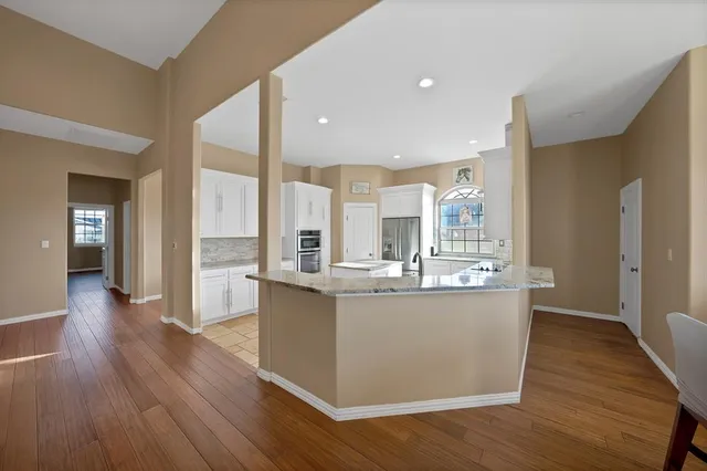 a view of a kitchen with kitchen island wooden floors and stainless steel appliances
