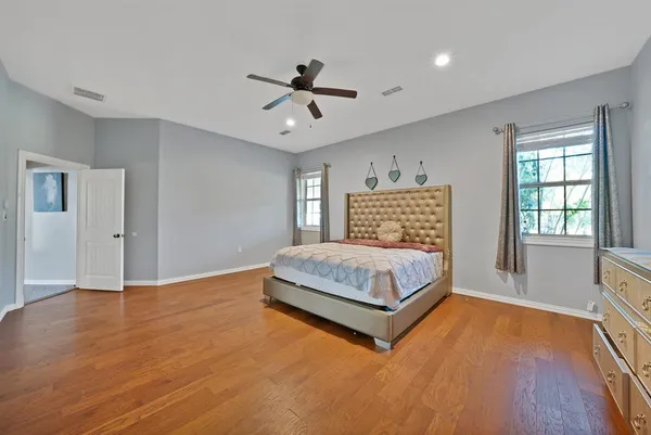 a bedroom with a large bed window and wooden floor