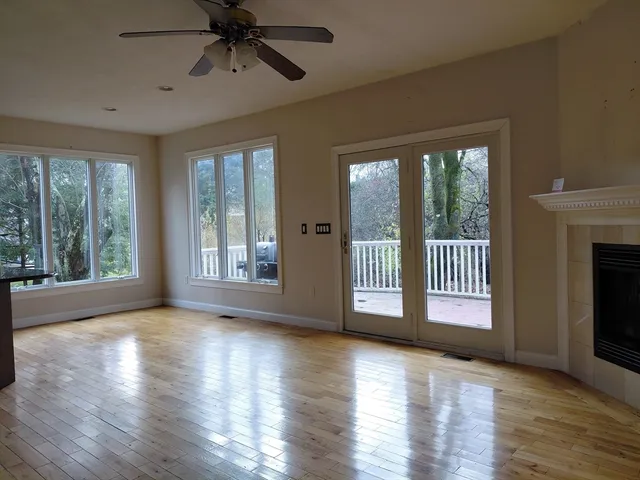 a view of an empty room with a window and wooden floor