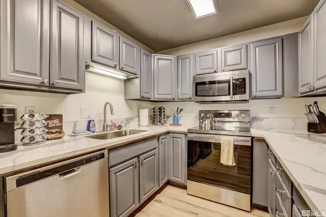 a kitchen with stainless steel appliances granite countertop a sink dishwasher stove and microwave with wooden cabinets