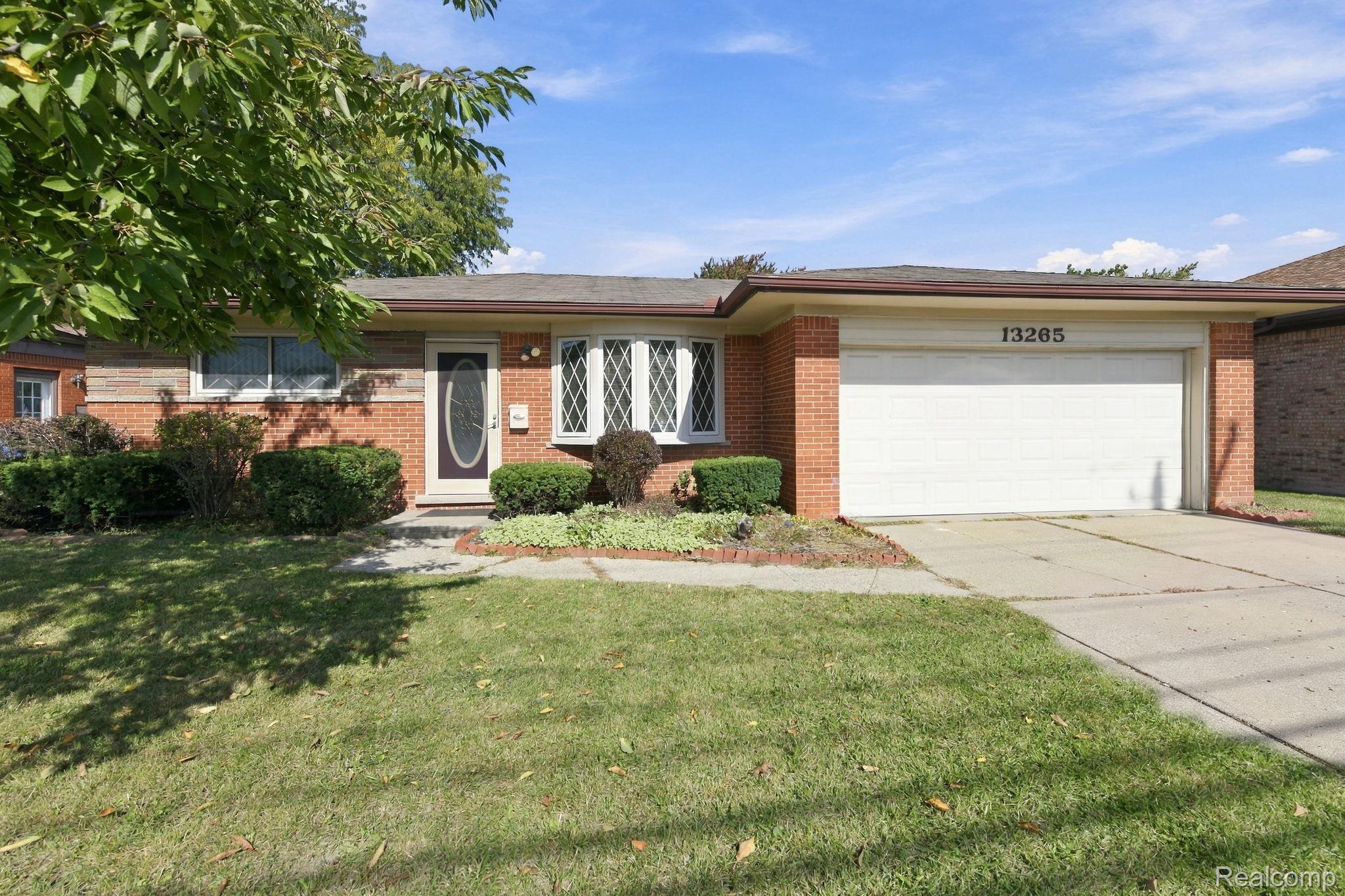 13265 12 Mile Road Warren, MI 48088 - Photo 1 of 33 Red brick exterior with a white garage door, featuring decorative bay windows and a front entry door with an oval glass insert