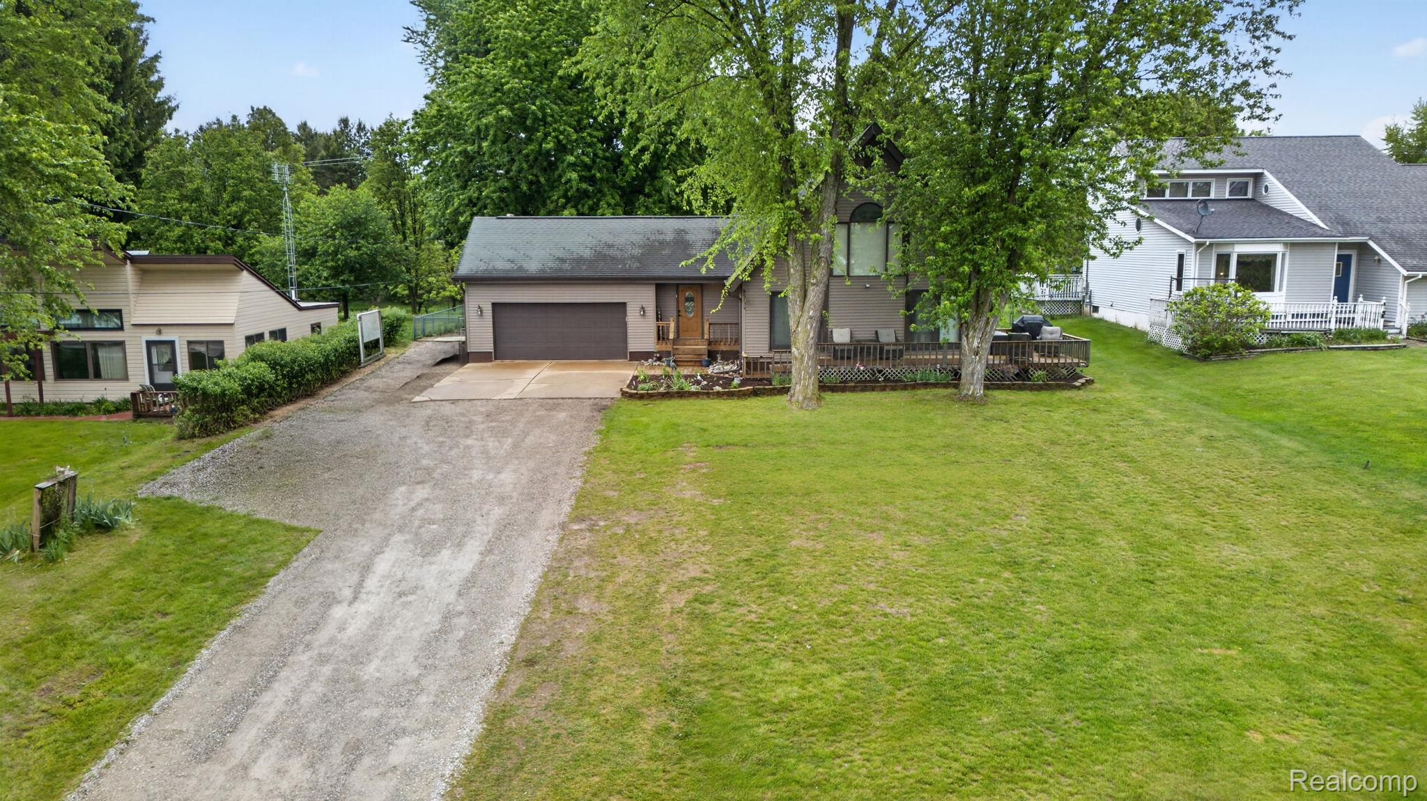1280 Petts Road Fenton, MI 48430 - Photo 59 of 62 View of front of property featuring concrete driveway, a front yard, a wooden deck, and a garage
