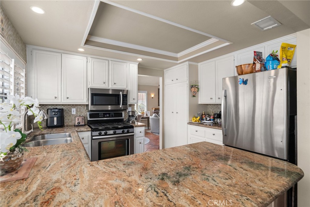 19422 Totem Court Riverside, CA 92508 - Photo 13 of 44 a kitchen with refrigerator a microwave a stove and white cabinets with wooden floor