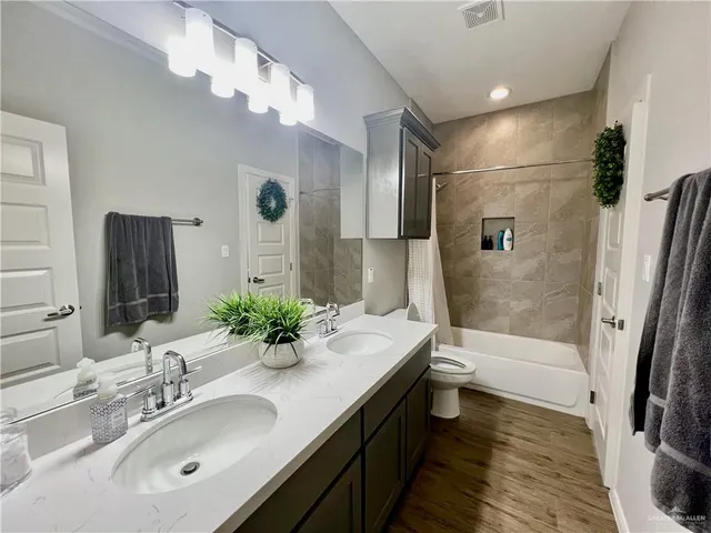 a bathroom with a granite countertop sink a toilet a mirror and shower