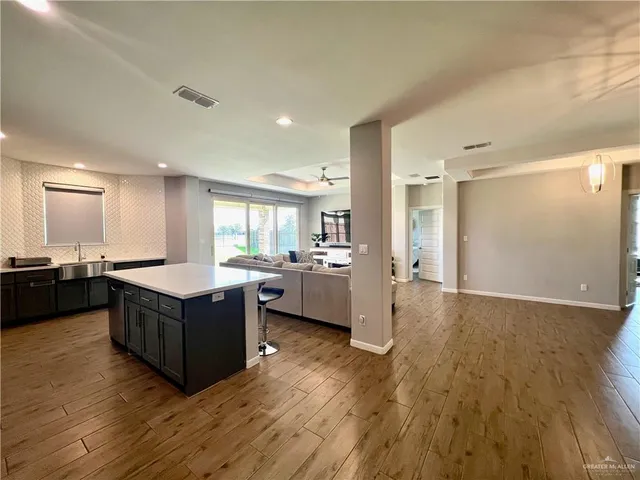 a kitchen with kitchen island wooden floors appliances and cabinets
