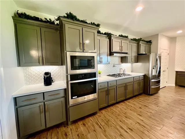 a kitchen with stainless steel appliances a stove microwave and a refrigerator