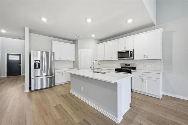 a kitchen with white cabinets and stainless steel appliances