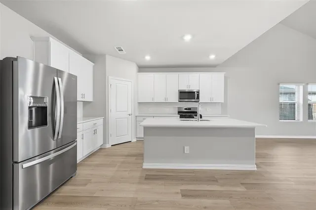 a kitchen with stainless steel appliances granite countertop a refrigerator stove a sink and a oven with wooden floor