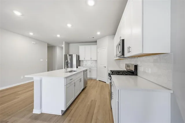 a kitchen with white cabinets sink and stainless steel appliances