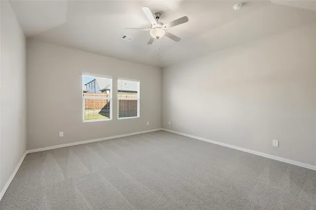 an empty room with windows and ceiling fan